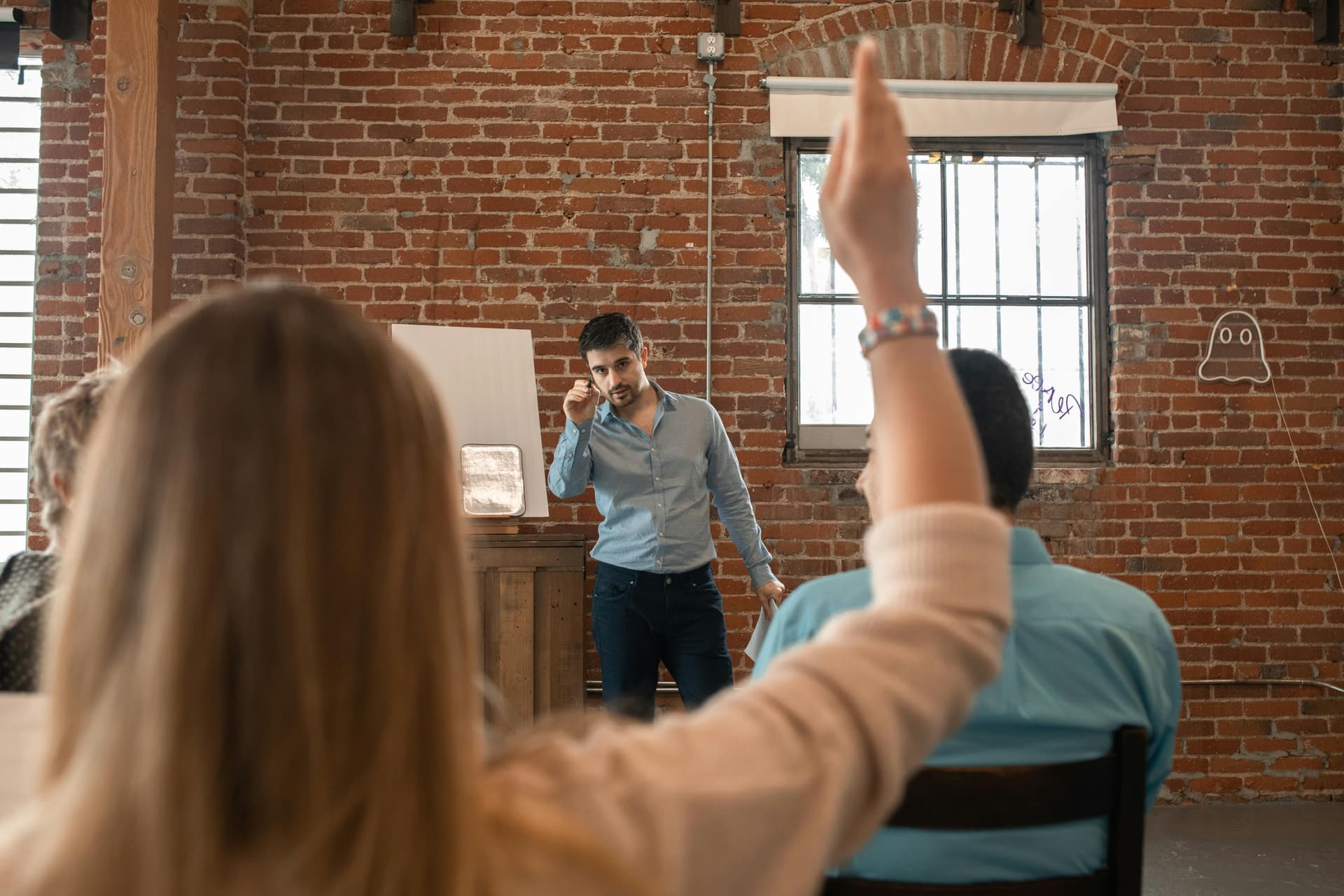 Un entrepreneur répond à une question durant un atelier de formation dans un espace en briques, ambiance décontractée et engagée.