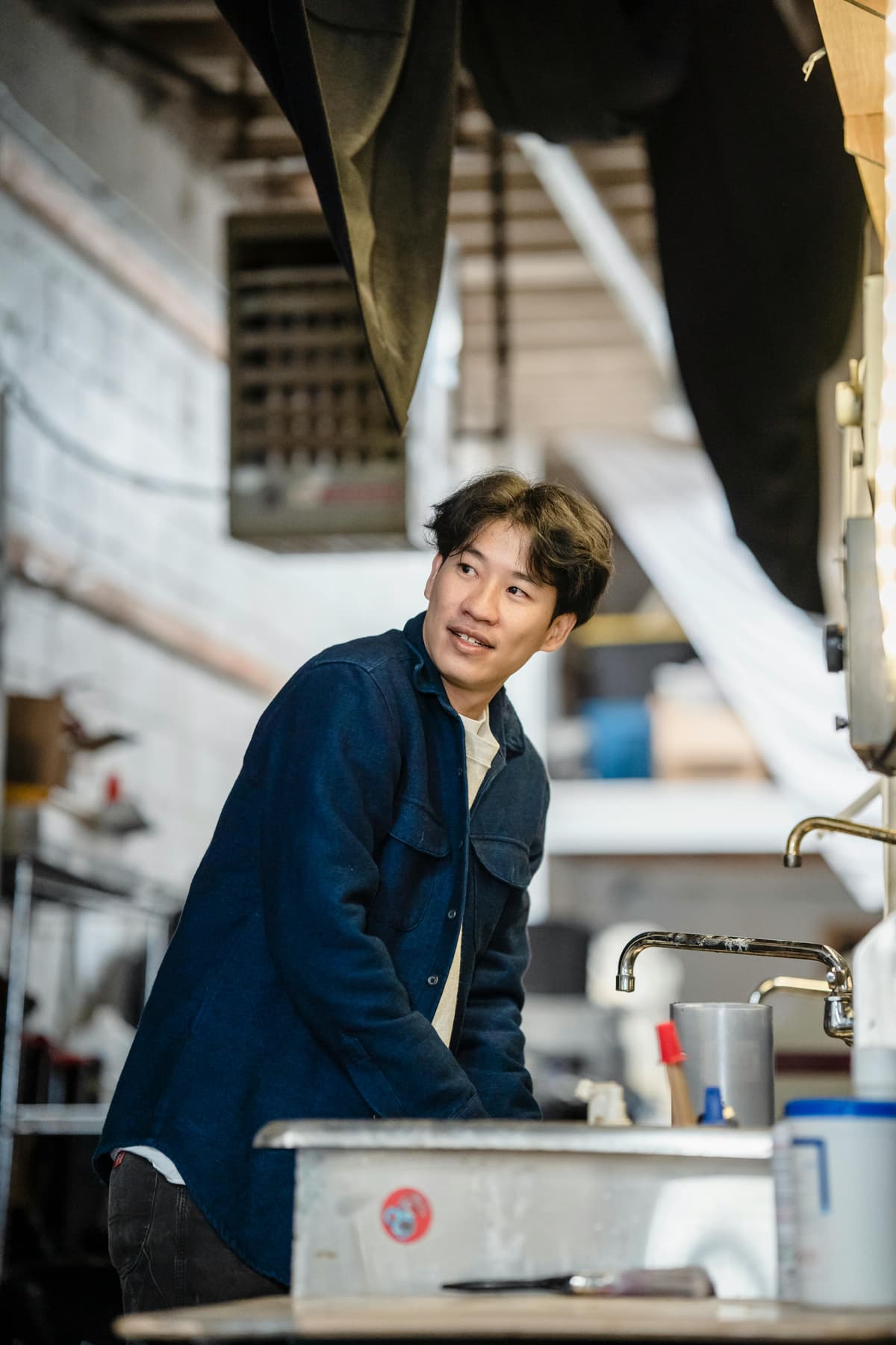 Portrait d’un jeune homme souriant dans un atelier artisanal, incarnant une production humaine et responsable.
